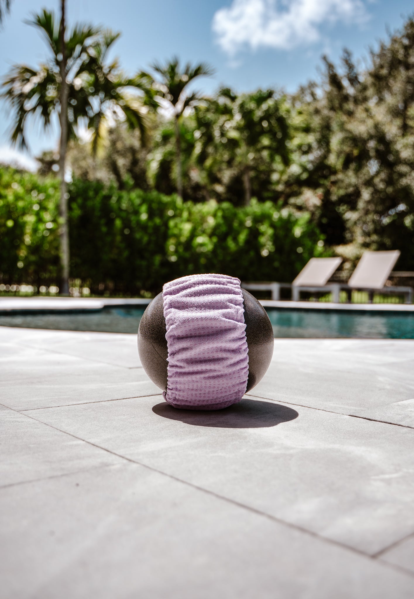 Lavender Grip Happens band wrapped around a Pilates ball beside a pool